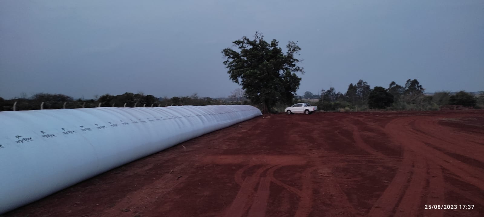 Silo-bolsa longo em terreno de terra vermelha
